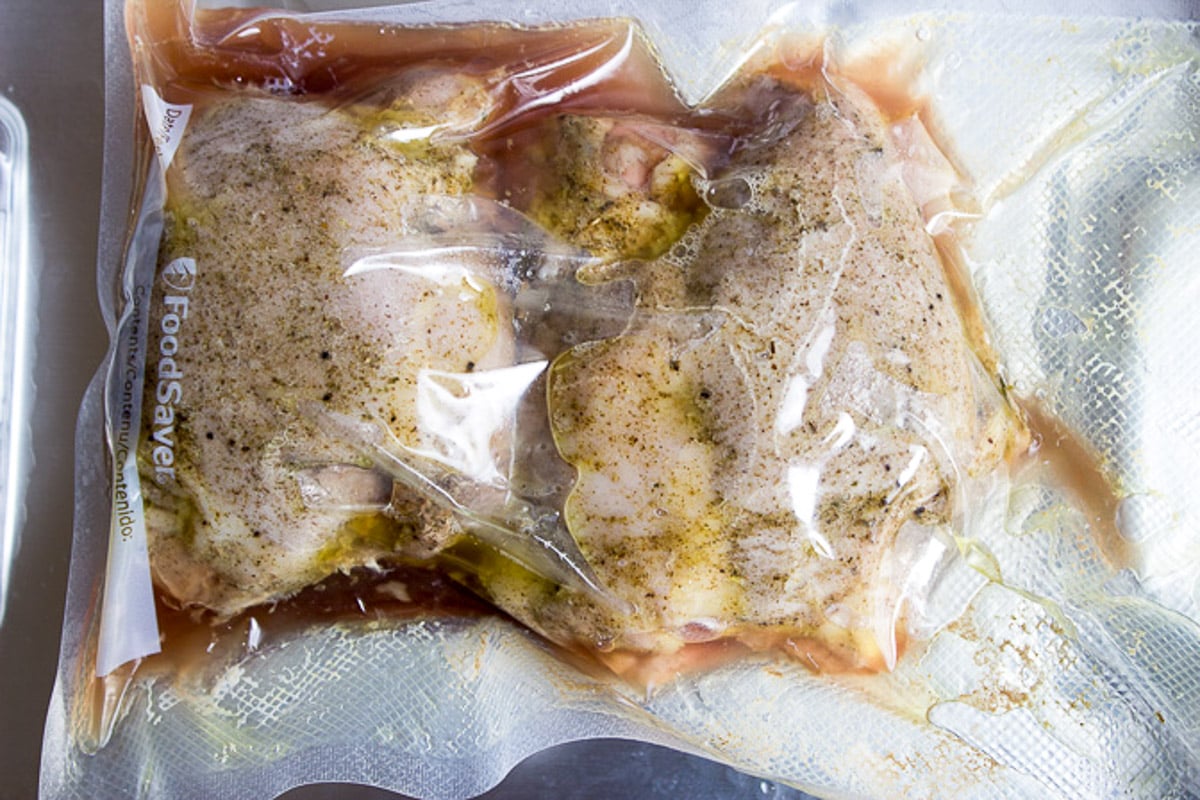 Two cooked turkey thighs in sous vide bag on paper towels.