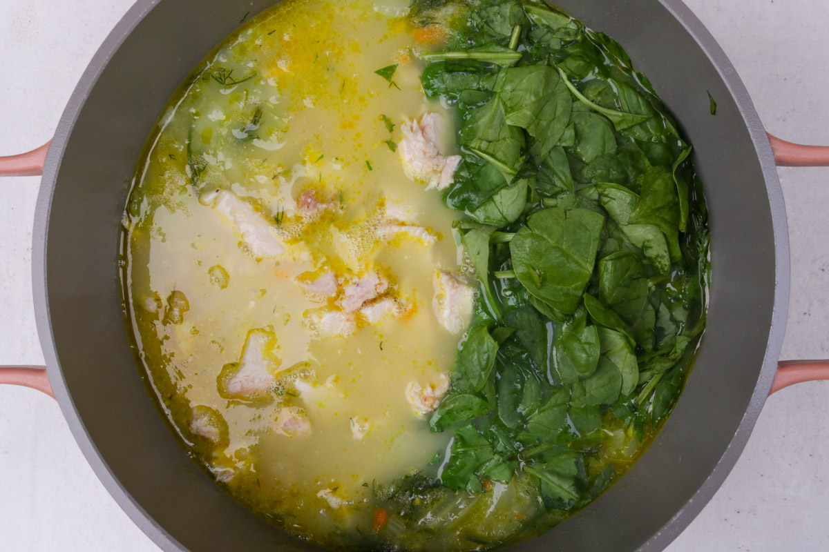 Chicken and spinach added to pot of chicken soup with veggies.